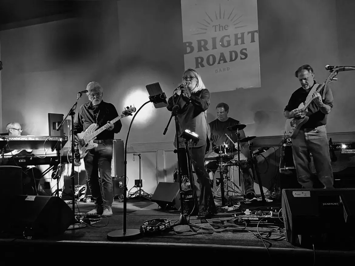 Black and white shot of the full Bright Roads Band under the band banner